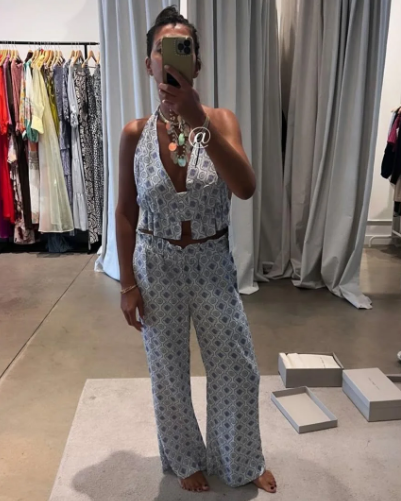 Woman taking a mirror selfie wearing a patterned set in a clothing store.