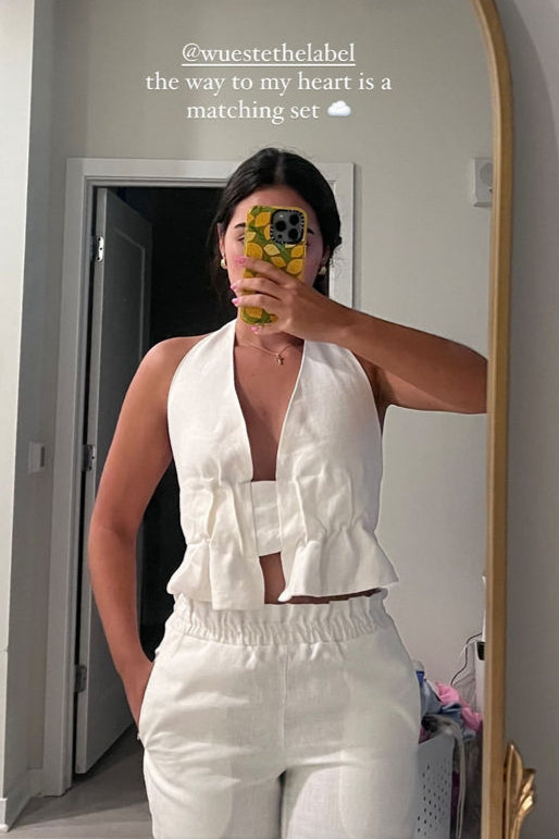 Person wearing a white outfit in front of a mirror